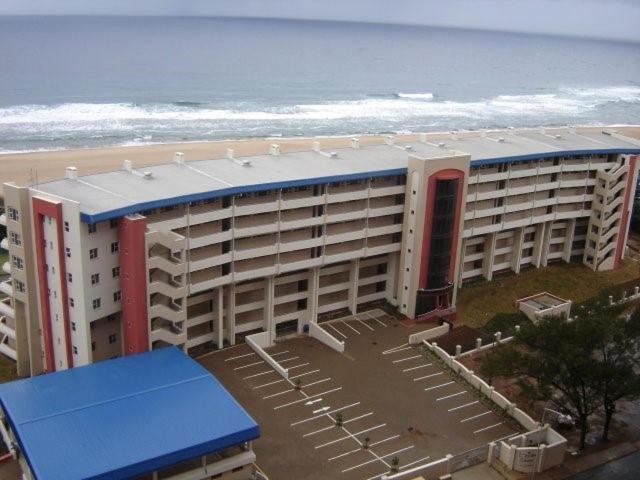 a large building with a blue roof next to the beach at 111 Lescalier Cabanas - Amanzimtoti in Amanzimtoti
