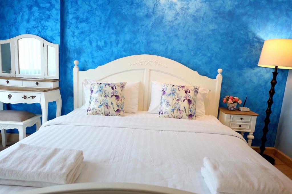1 dormitorio con cama blanca y pared azul en Marrakesh Huahin Condo, en Hua Hin