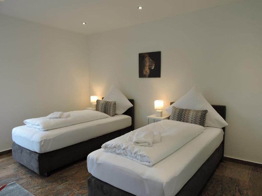 Cette chambre comprend 2 lits et une table avec des lampes. dans l'établissement Ferienwohnungen Fabry, à Sarrebruck