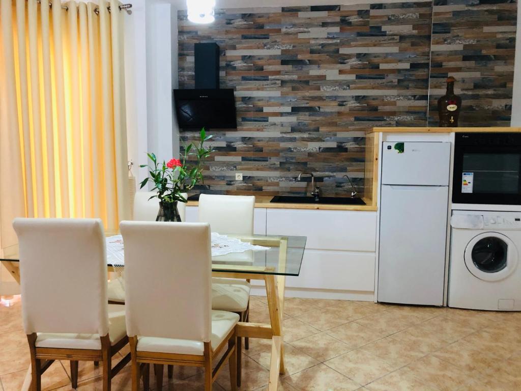 Flora Apartments Sarande في سارنده: غرفة طعام مع طاولة وكراسي ومطبخ