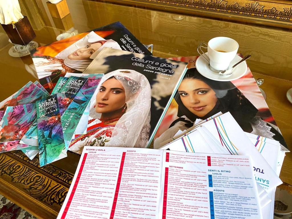 a table topped with books and a cup of coffee at Le Fresie B&B in SantʼAntìoco