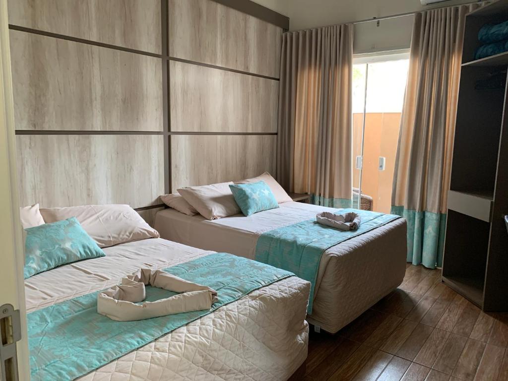 two beds in a hotel room with towels on them at Pousada Duas Ilhas in Penha
