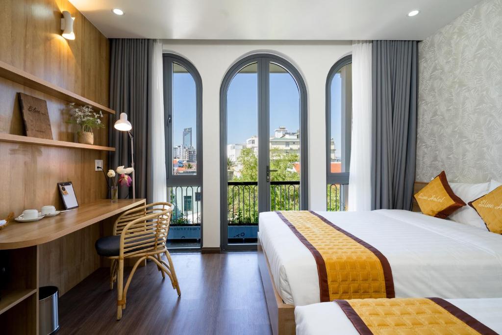 um quarto de hotel com uma cama, uma secretária e janelas em Sline Hotel em Hue