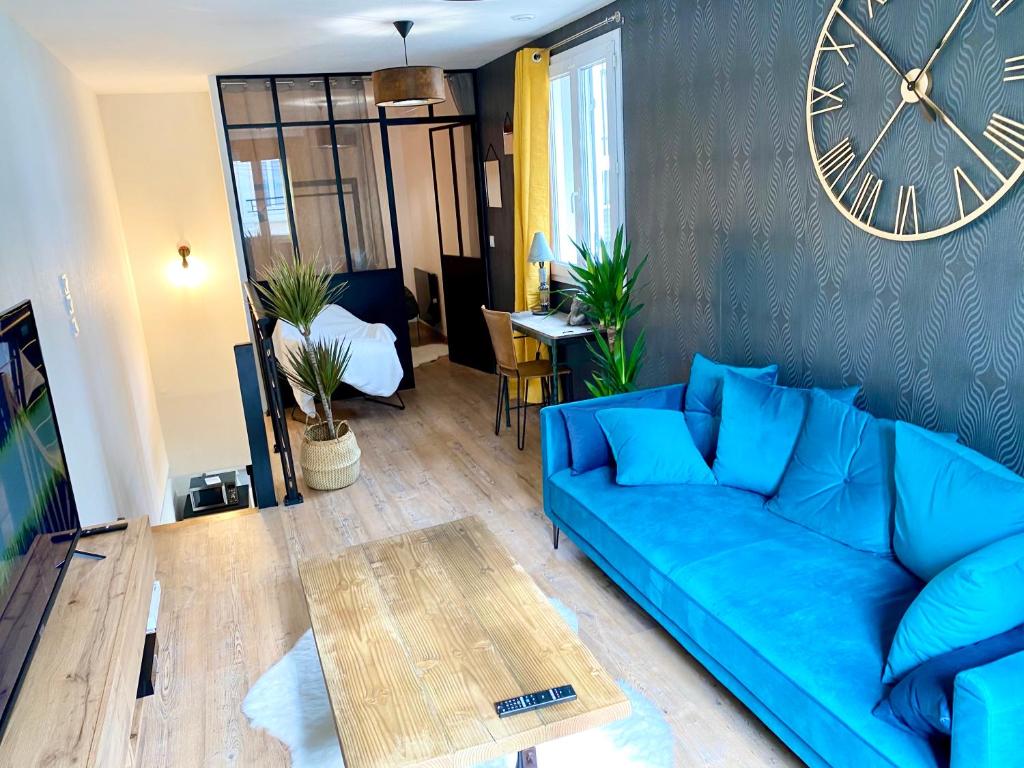 Sofá azul en la sala de estar con reloj en la pared en Maison cœur de ville esprit industriel - Le Loft12, en Châteauroux