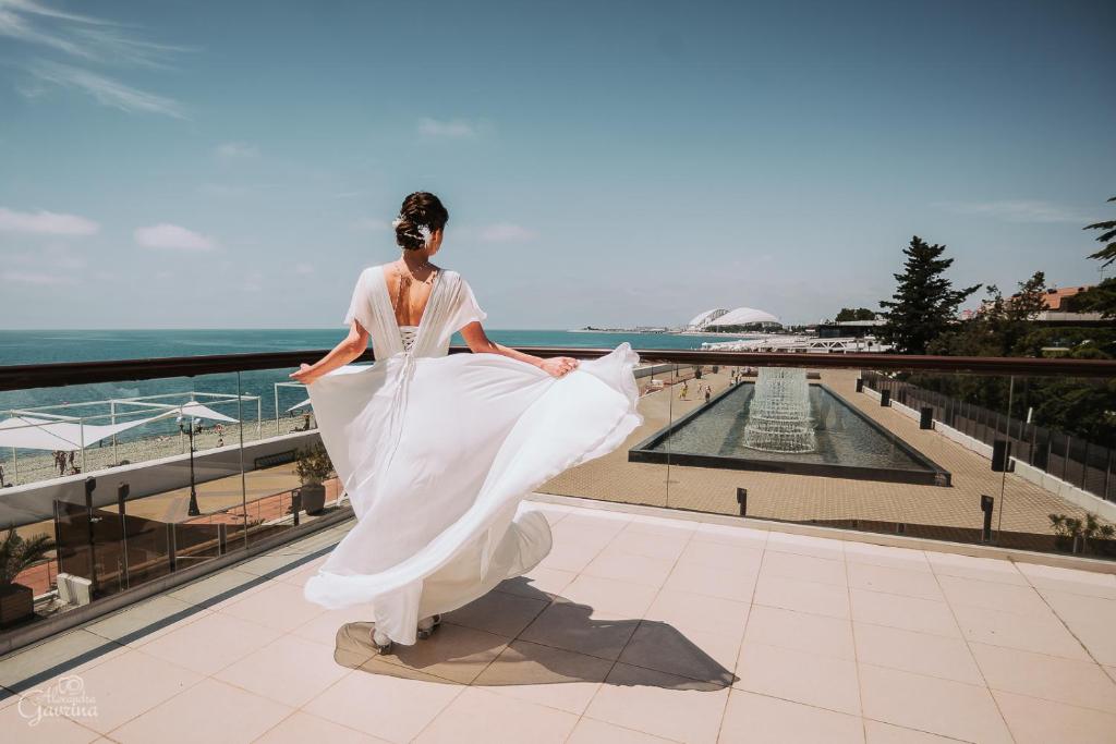 a woman in a wedding dress standing on a balcony at Arfa Park-Hotel in Adler