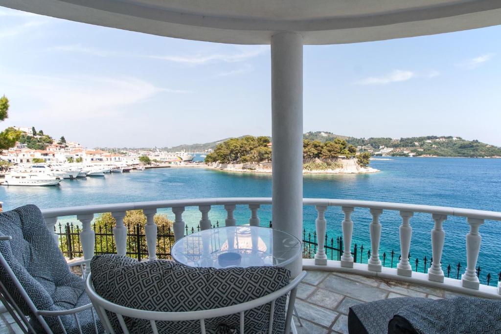 balcón con mesa, sillas y vistas al agua en ClubOrsa Ourania's Mansion, en Skiathos