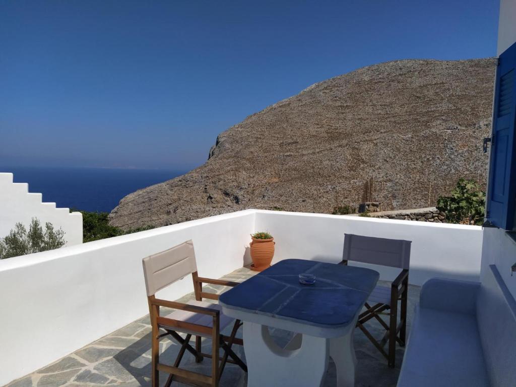 una mesa y sillas en un balcón con vistas al océano en Cycladic houses in rural surrounding, en Amorgós