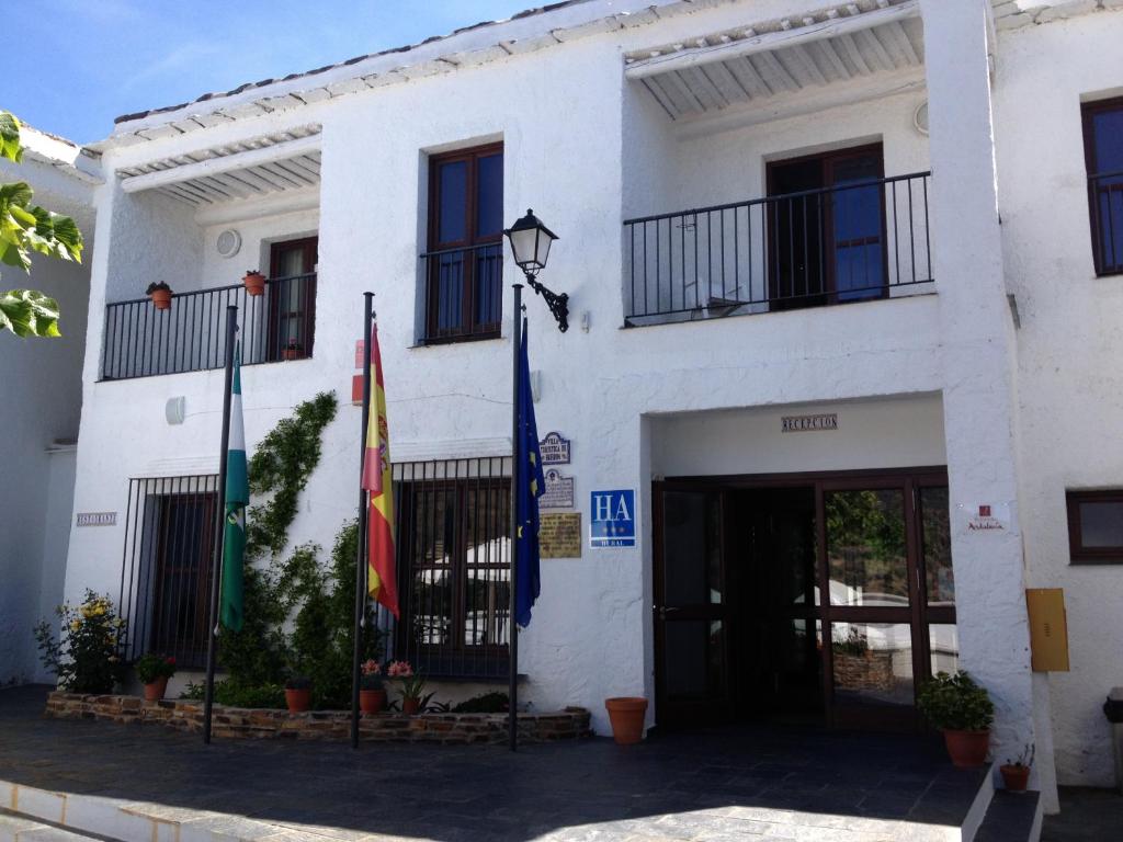 ein weißes Gebäude mit Flaggen davor in der Unterkunft Villa Turistica de Bubion in Bubión