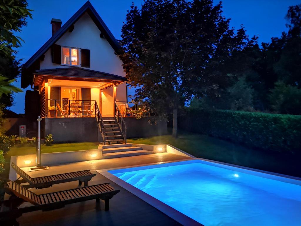 una piscina di fronte a una casa di notte di GreenHouse s bazenom a Otruševec