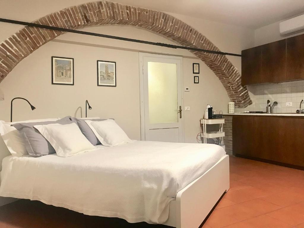 een slaapkamer met een groot wit bed en een keuken bij La Casa nel Vicolo in Altopascio