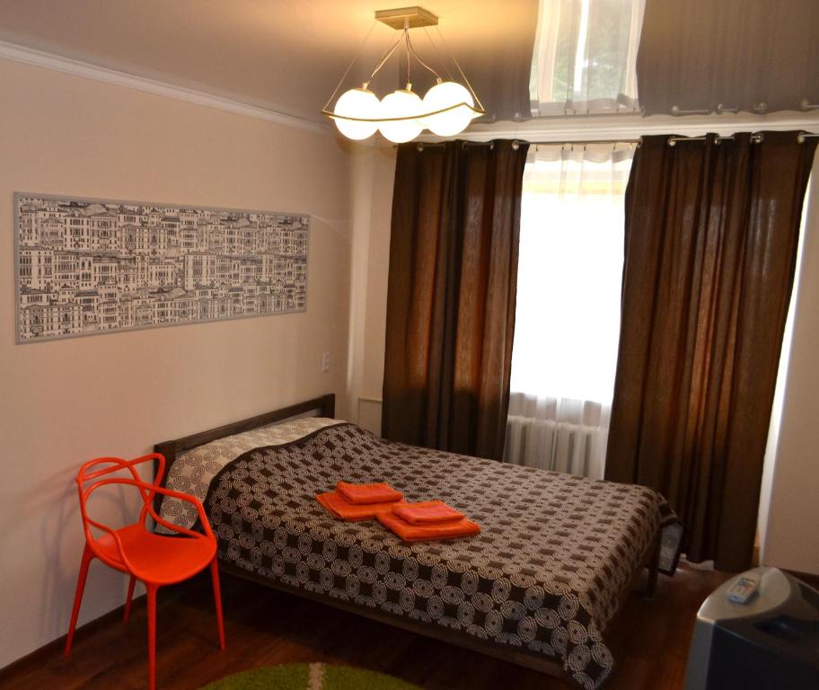 um pequeno quarto com uma cama e uma cadeira vermelha em Соборная Апартаменты em Kamianets-Podilskyi