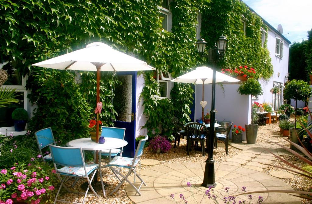 a patio with two tables and two umbrellas at Admiral Blake Guesthouse in Bridgwater