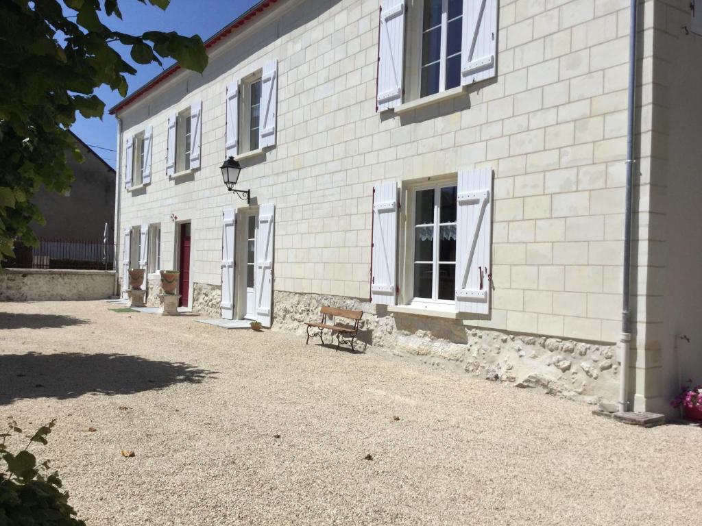 a white brick building with a bench in front of it at Les tilleuls de Mary in Rillé