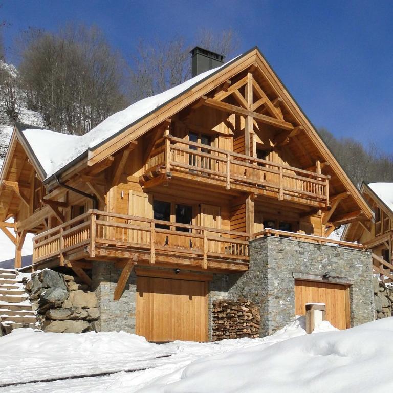 une cabane en rondins entourée d'une terrasse dans la neige dans l'établissement Chalet Skidh - 10 personnes - emplacement idéal au centre de Vaujany, à Vaujany