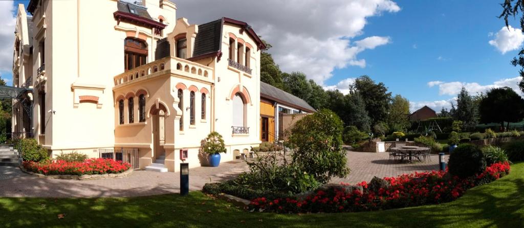 ein großes Gebäude mit Blumen davor in der Unterkunft Le Manoir de la mantille in Caudry