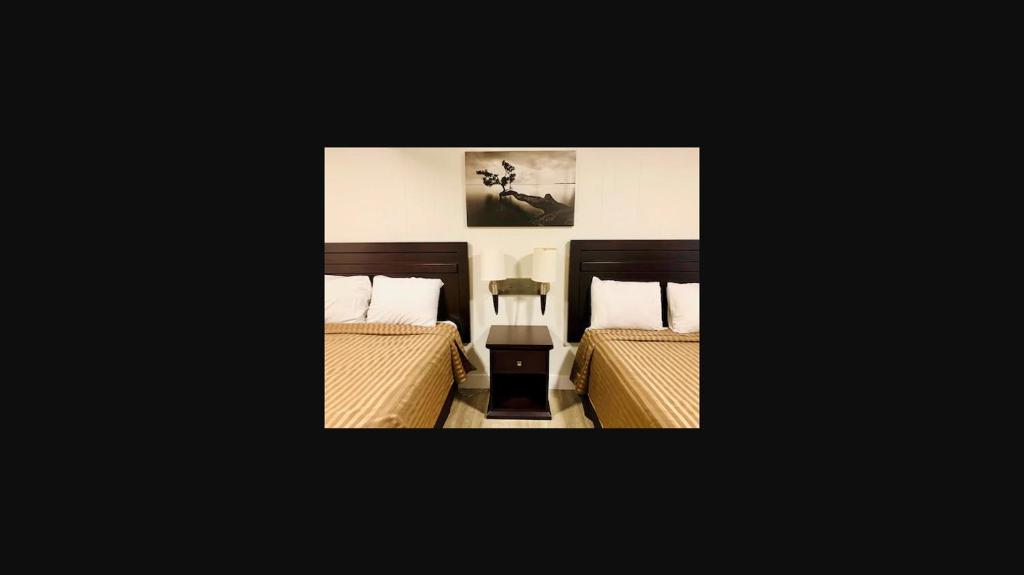a bedroom with two beds and a picture on the wall at Traveler's Motel Penticton in Penticton