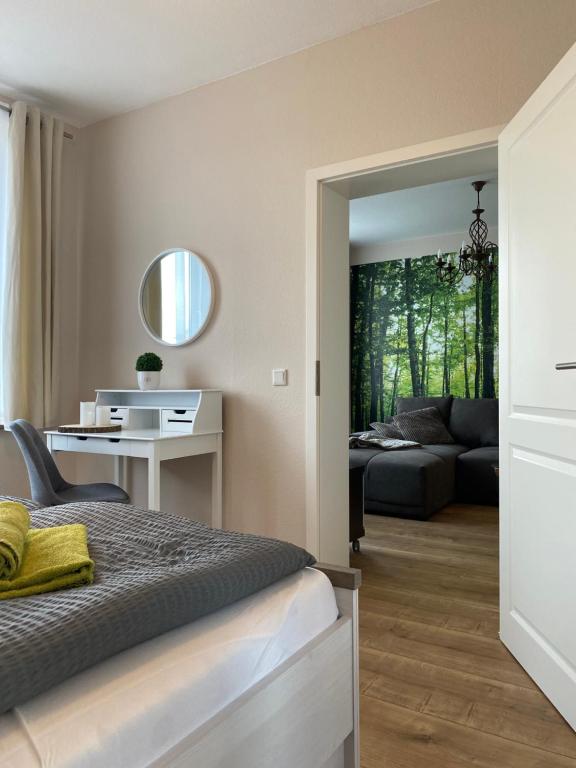 een slaapkamer met een bed, een bureau en een bank bij Ferienapartments HarzZeit in Wernigerode