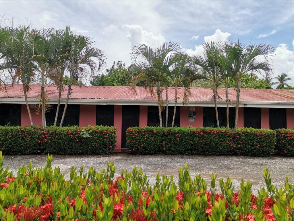 un edificio rosso con palme e fiori di Cabinas Alemar a Paquera