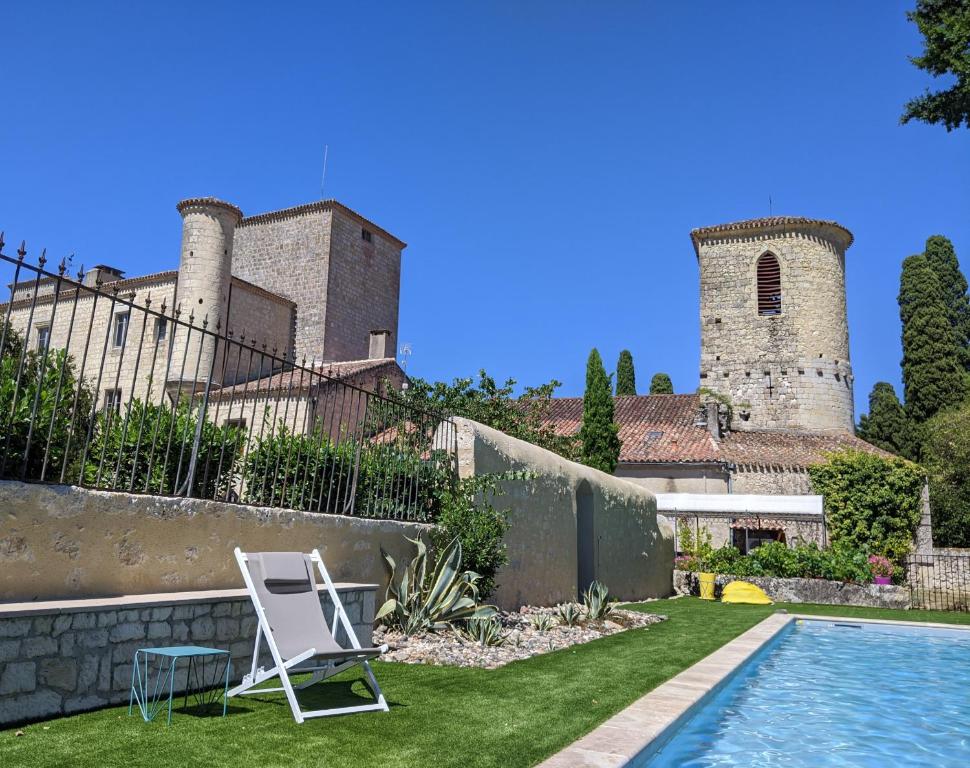 un patio con piscina, una silla y un castillo en Château des Fousseries, en Condom