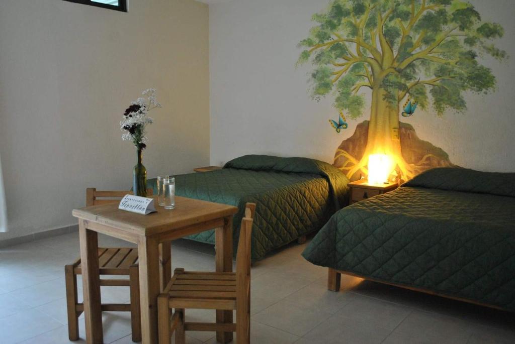 um quarto com duas camas e uma mesa e um mural de árvore em El Amate em Tepoztlán