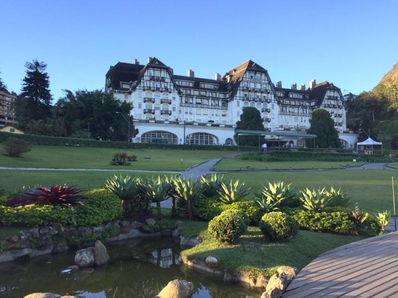 un grand bâtiment blanc avec un jardin et un étang dans l'établissement Petrópolis Palácio Quitandinha, à Petrópolis