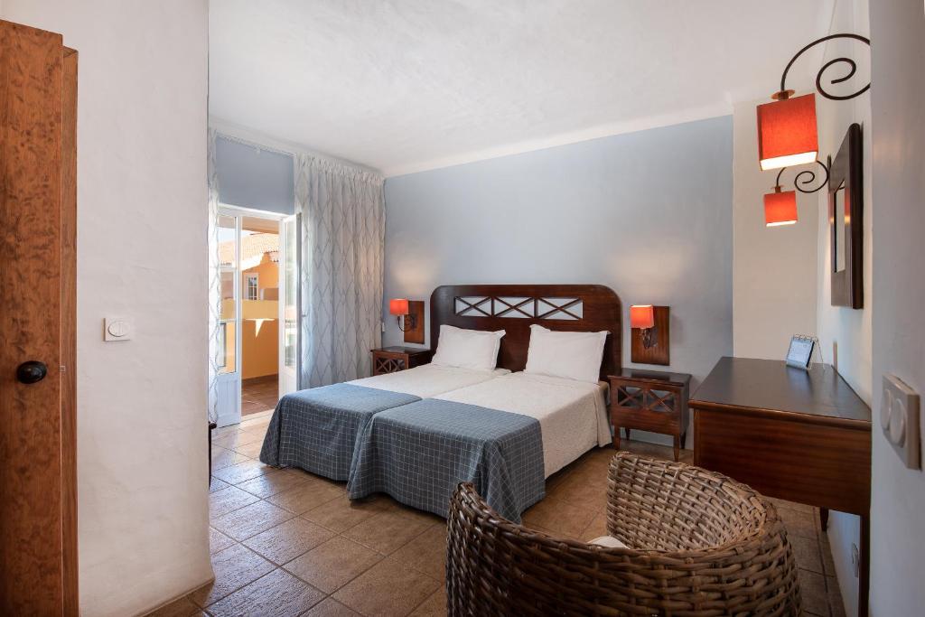 een slaapkamer met een bed, een tafel en een stoel bij Hotel Rural Monte da Leziria in Santo André