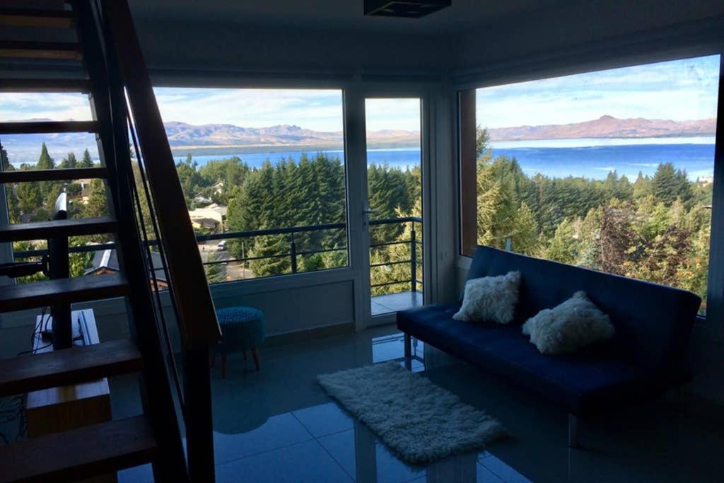 a living room with a blue couch and large windows at "Corazon al sur" departamento con vista única al Huapi in San Carlos de Bariloche