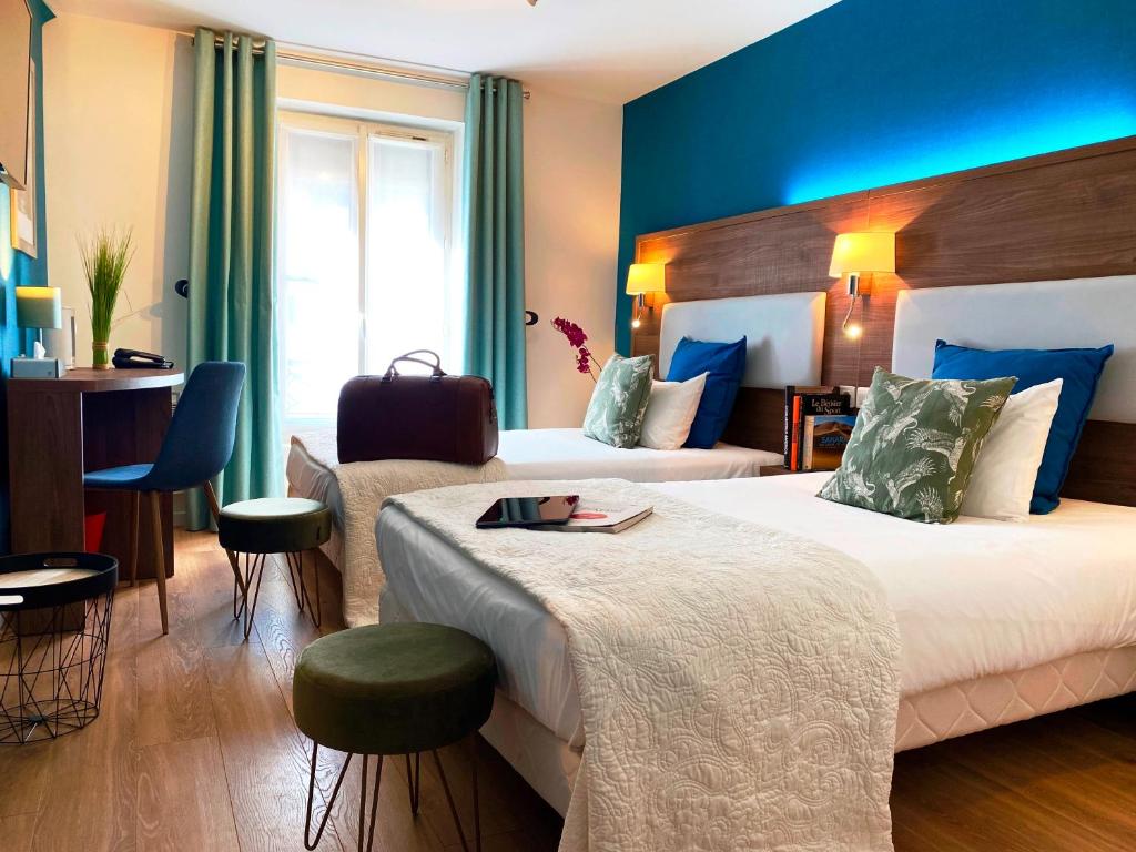 パリにあるホテル クレールフォンテーヌのベッド2台とデスクが備わるホテルルームです。