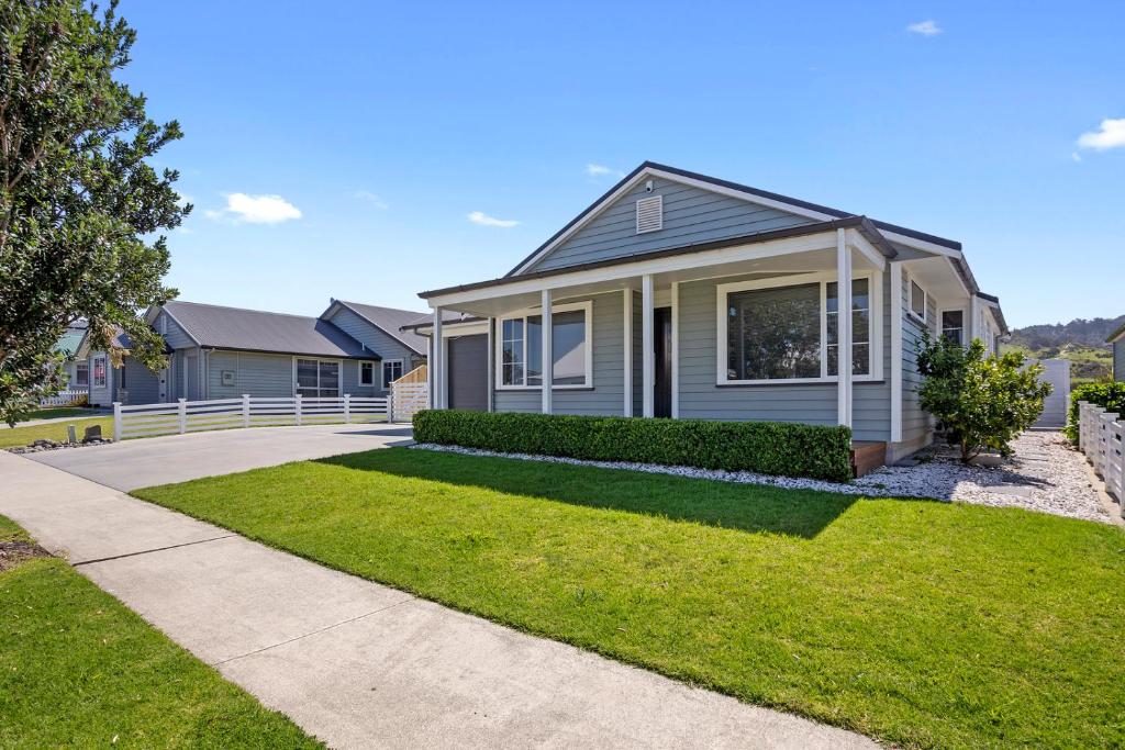a house with a green lawn in front of it at Sky Blue Retreat - Waihi Beach Holiday Home in Waihi Beach