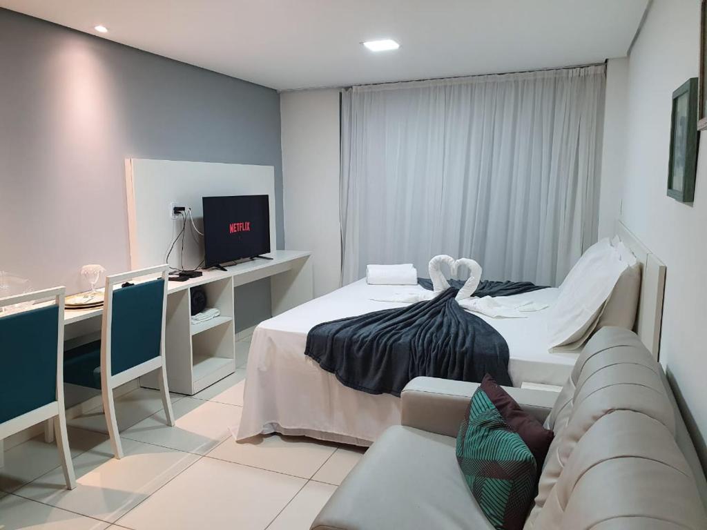 Cette chambre comprend un lit, un canapé et une télévision. dans l'établissement Laguna Beach Flat, à Porto de Galinhas