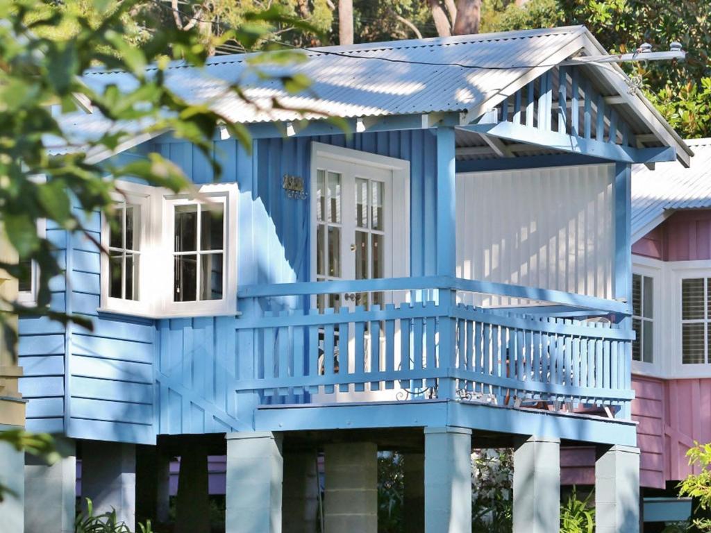 a blue house with a porch and a balcony at Cottage 5 Hyams Beach Seaside Cottages in Hyams Beach