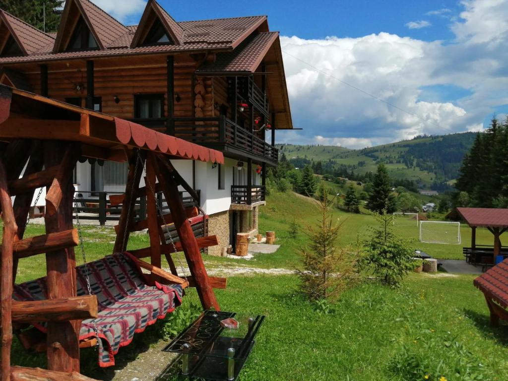 a log house with a swing in the yard at Pensiunea Waldhaus - Vatra Dornei in Vatra Dornei