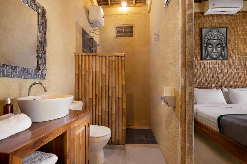 ein Badezimmer mit Waschbecken und Toilette und ein Bett in der Unterkunft Nusa Majesty in Nusa Penida