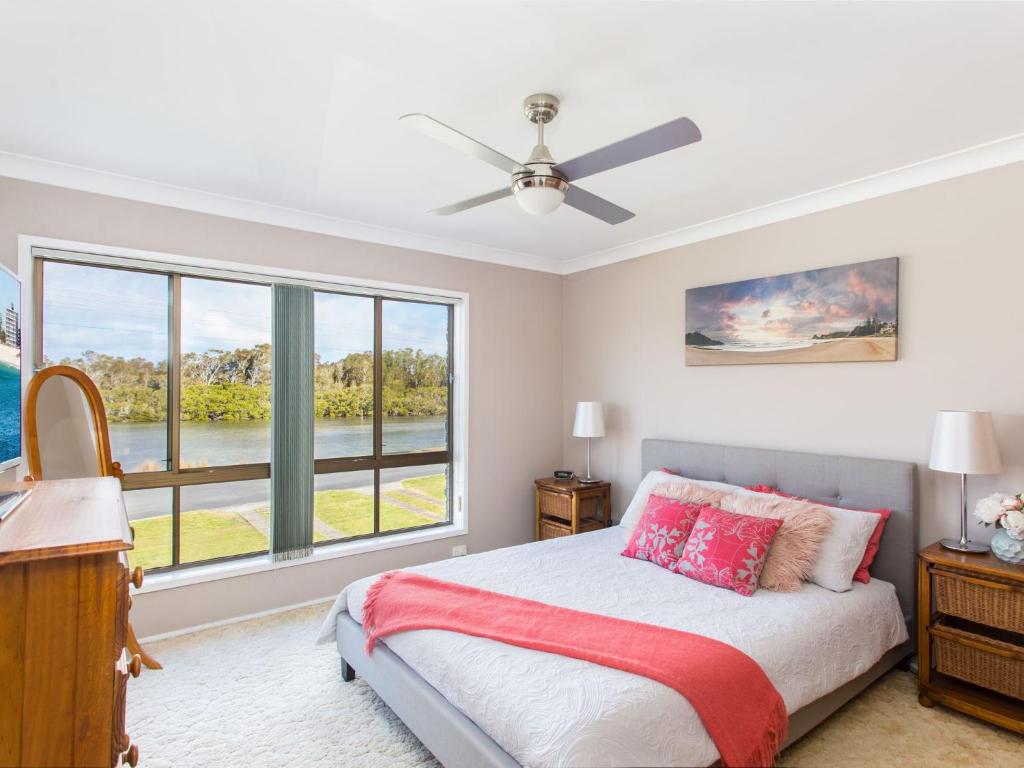 a bedroom with a bed and a large window at Waterside at Point Road in Tuncurry