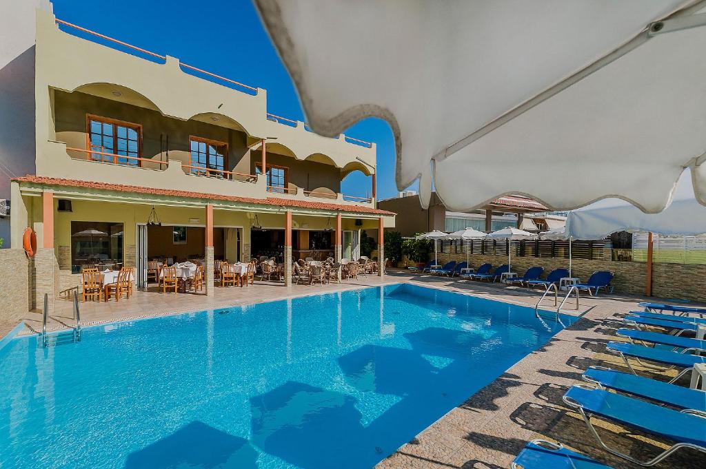 克雷馬斯蒂的住宿－埃斯梅拉達酒店，一座带蓝色椅子的建筑前的游泳池