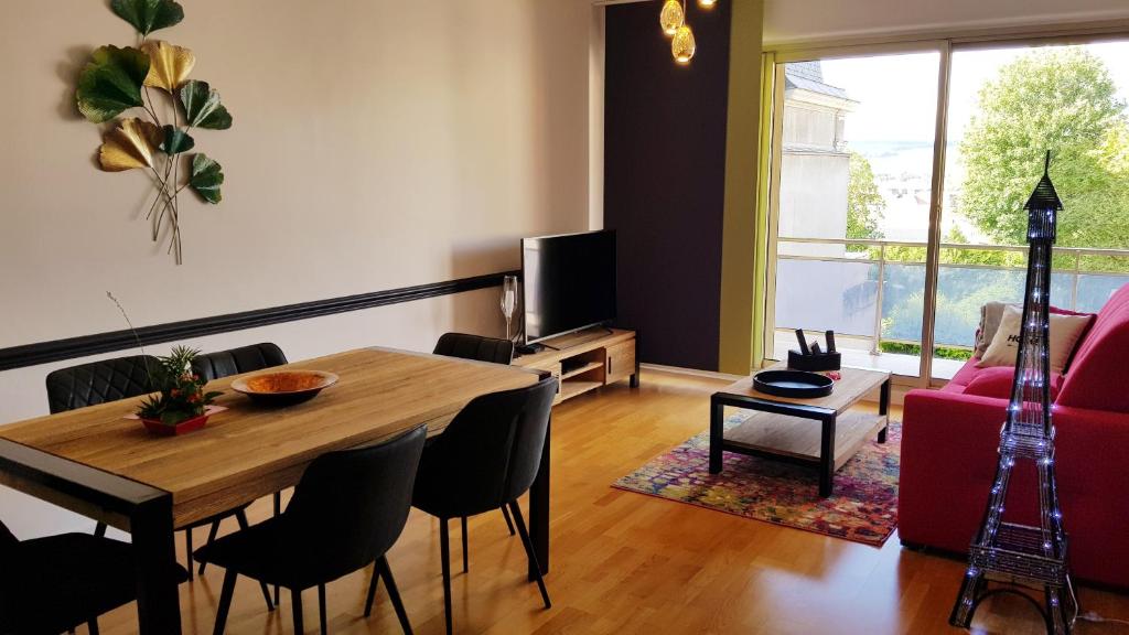 sala de estar con mesa de madera y sofá rojo en L'épopée de l'Avenue - Parking - Avenue de Champagne - Epernay en Épernay