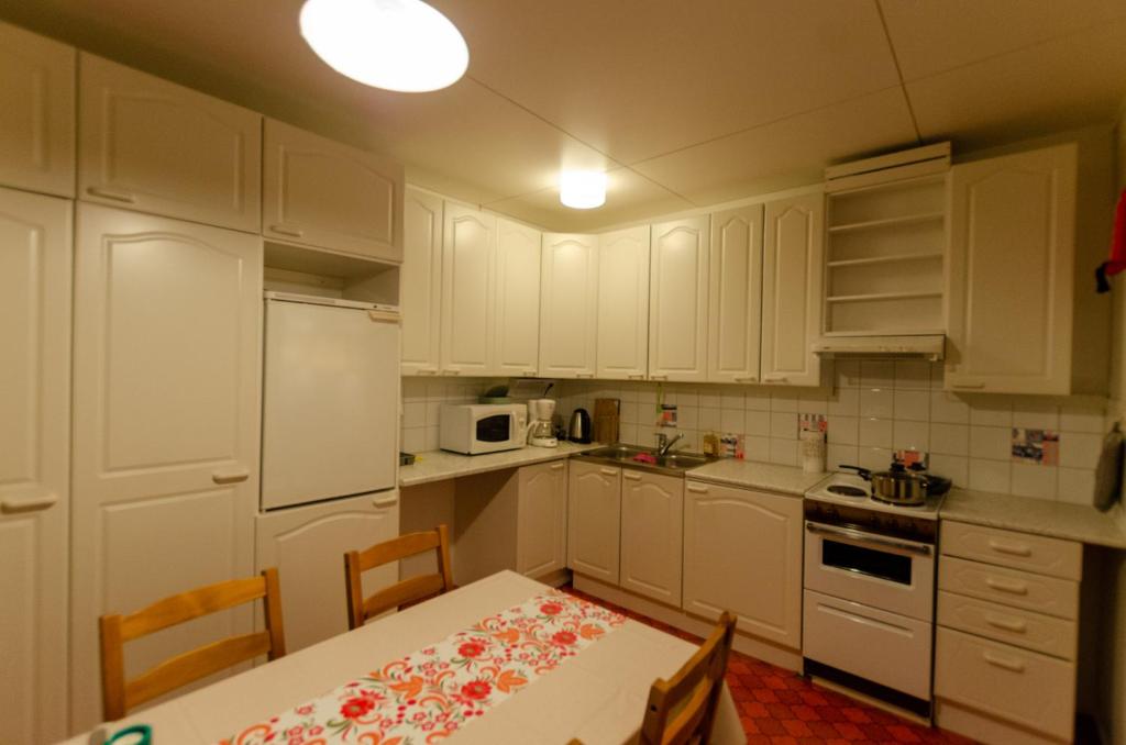 Una cocina con gabinetes blancos y una mesa y sillas. en Lokkankoti A, en Lokka