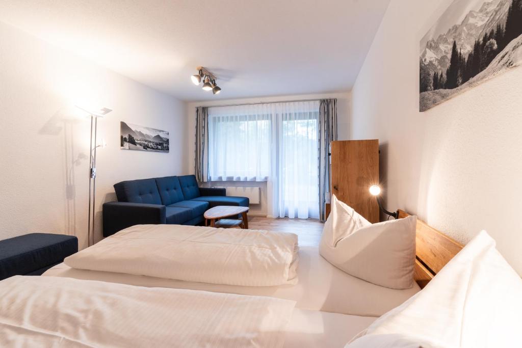 ein Hotelzimmer mit 2 Betten und einem blauen Sofa in der Unterkunft Ferienwohnungen Sattler in Oberstdorf
