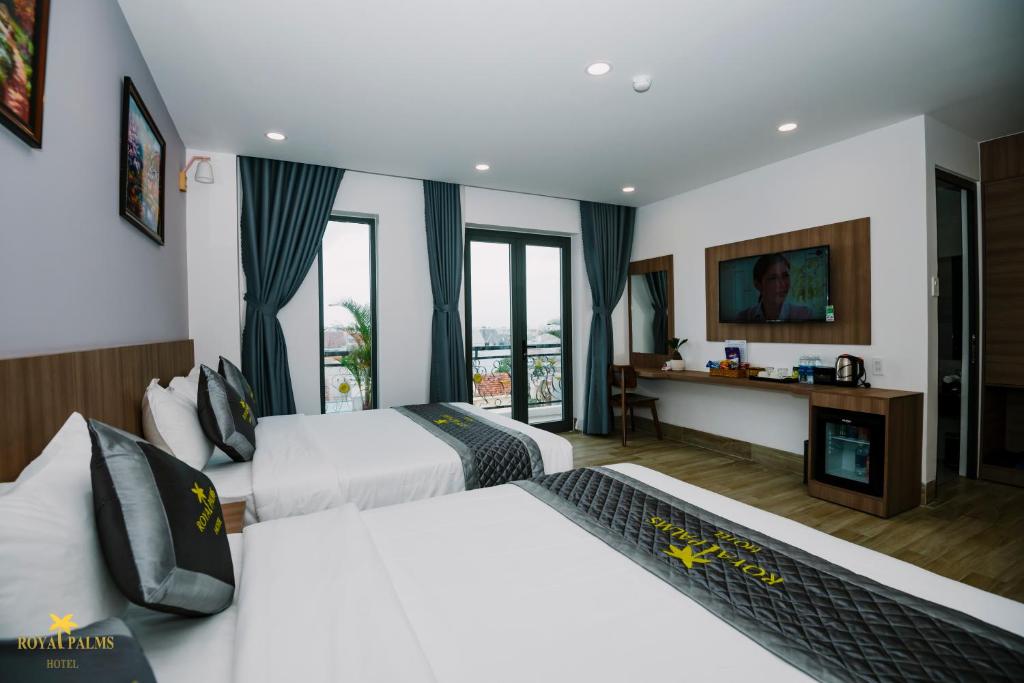 a hotel room with two beds and a desk at Royal Palms Hotel in Tuy Hoa