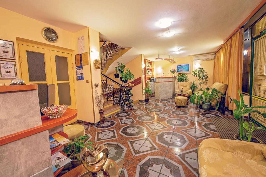a hallway with a tile floor with plants in it at Hotel Color in Varna City
