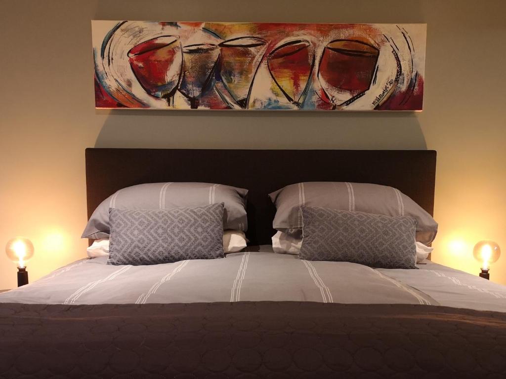 een bed met twee kussens en een schilderij aan de muur bij De Eppenbeek in Swalmen