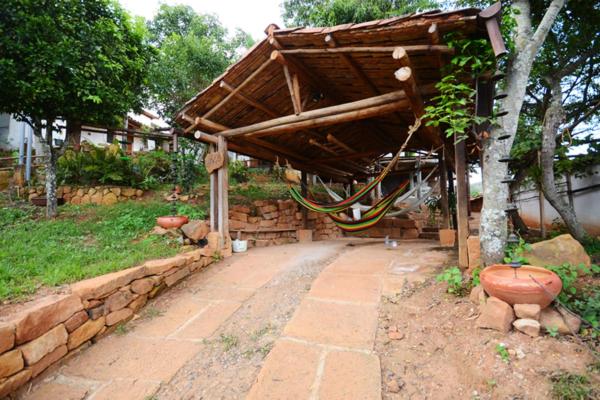 a building with a wooden roof and a stone wall at Tinto Hostel in Barichara