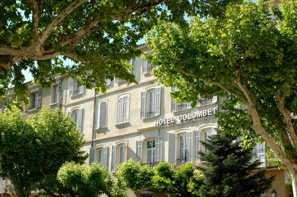 un gran edificio blanco con un cartel. en Hôtel Colombet en Nyons