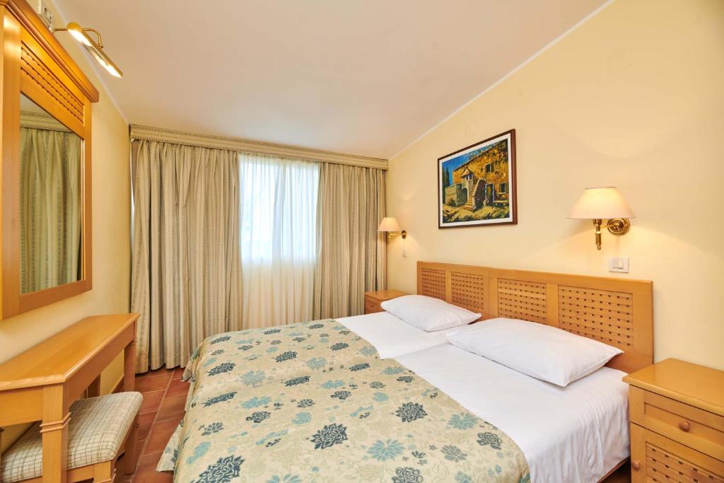 a hotel room with a bed and a window at Apartments Bellevue Plava Laguna in Poreč