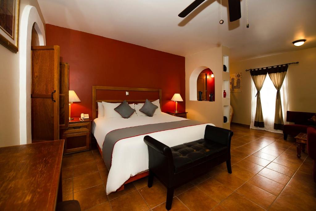 a bedroom with a large bed and a black chair at La Casona Tequisquiapan Hotel & Spa in Tequisquiapan