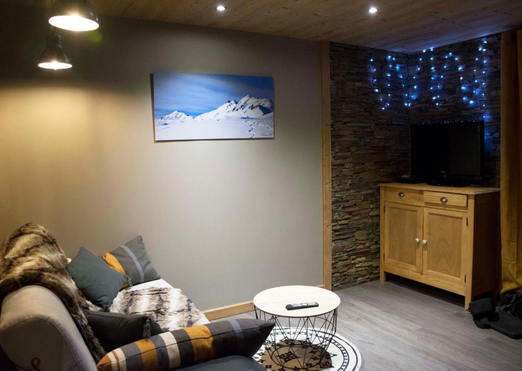 a living room with a couch and a tv at Appartement 3 étoiles - au pied des pistes in Valmeinier