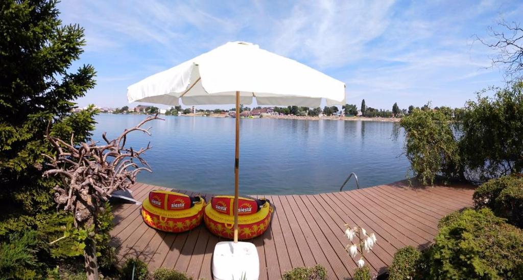 two chairs and an umbrella on a dock next to the water at TopSenec-Lakeside Home in Senec