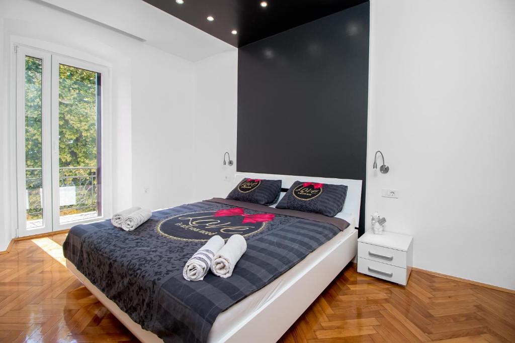 a bedroom with a large bed with black and white sheets at Apartmani Dada in Rijeka