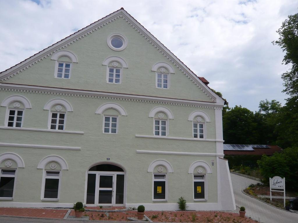 ein großes weißes Haus mit einem Turm in der Unterkunft Pension Lechner in Vilsbiburg