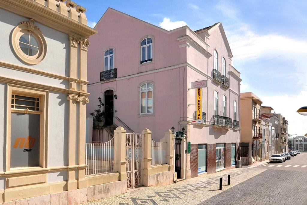 un edificio rosa al lado de una calle en Central Guest House en Figueira da Foz